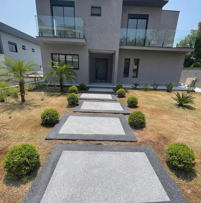 Caminho de entrada em pedras de Fulget claro sobre faixa escura, entre o jardim